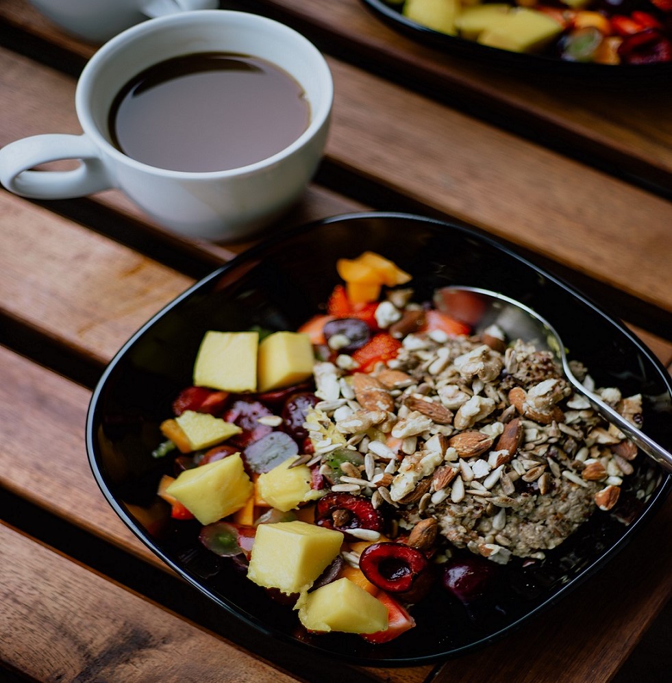 Bowl of fruits and nuts with mug of coffee